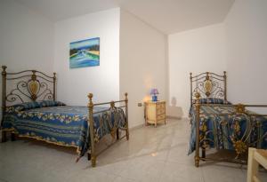 1 dormitorio con 2 camas y vestidor con lámpara en Villetta Orchidea, en Gagliano del Capo