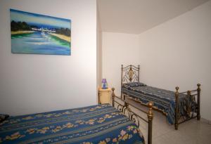 1 dormitorio con 2 camas y un cuadro en la pared en Villetta Orchidea, en Gagliano del Capo