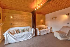 Habitación con 2 camas blancas y paredes de madera. en Le Bois Joly, en La Giettaz