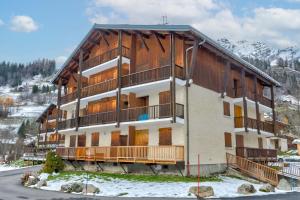 un gran edificio de apartamentos en las montañas con nieve en Le Bois Joly, en La Giettaz