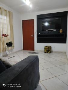 sala de estar con TV de pantalla plana en la pared en Casa mobiliada, en Campo Grande