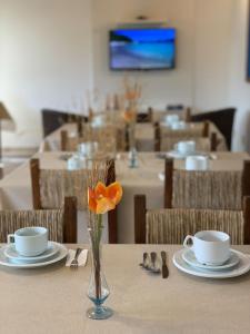 a table with two cups and a vase with a flower at Hotel Natur Campeche in Florianópolis