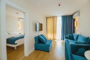 a hotel room with a bed and a blue couch at Orbi City Sea View Apartments in Batumi