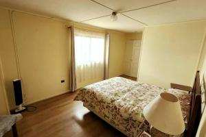 een slaapkamer met een bed, een lamp en een raam bij Cabaña familiar in Cochrane