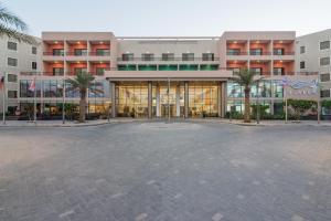a large building with palm trees in front of it at Alreem Village Hotel in Al Jubail