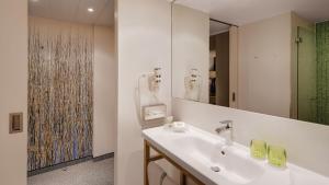 ein weißes Badezimmer mit einem Waschbecken und einem Spiegel in der Unterkunft Holiday Inn Frankfurt - Alte Oper, an IHG Hotel in Frankfurt am Main