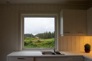 a kitchen with a window over a sink and a field at Vollvaagen Apartments Smøla, boat included in Smøla