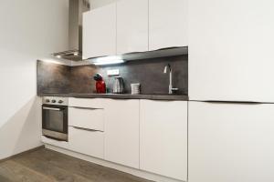 una cocina con armarios blancos y fregadero en Apartments / 10 min from center / O2 ARENA, en Praga