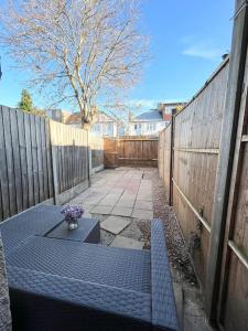 a blue bench in a backyard with a fence at Spacious flat with patio garden in Raynes Park