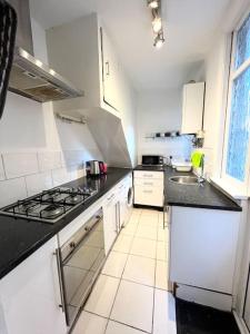 a white kitchen with a stove and a sink at Spacious flat with patio garden in Raynes Park