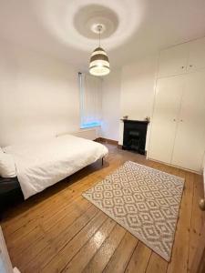 a bedroom with a bed and a rug on a wooden floor at Spacious flat with patio garden in Raynes Park