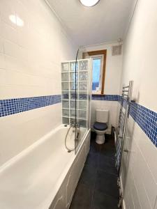 a bathroom with a tub and a toilet in it at Spacious flat with patio garden in Raynes Park