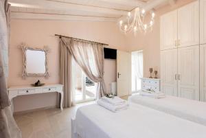 a white bedroom with two beds and a chandelier at Villa Frosso in Kalami +34 photos