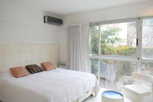 a bedroom with a white bed and a large window at Syrah Studios in Buenos Aires