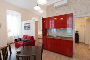 een keuken en een woonkamer met rode kasten en een tafel bij Rooms Boutique Carducci in Trieste