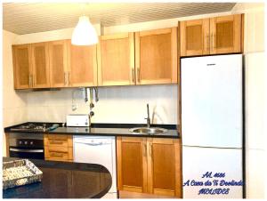 a kitchen with wooden cabinets and a white refrigerator at A Casa da Ti Deolinda in Melides