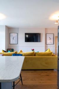 a living room with a yellow couch and a tv at Stylish Beachfront Bolthole with Stunning Sea Views and Luxury Touches in Herne Bay