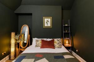 1 dormitorio con cama y espejo en JOIVY Contemporary cottage with parking, en Edimburgo