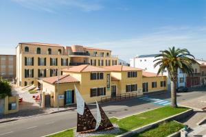 un edificio amarillo con una palmera y una calle en MuMA Hostel, en SantʼAntìoco