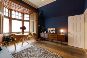 sala de estar con paredes azules, mesa y sillas en JOIVY Contemporary cottage with parking, en Edimburgo