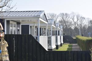 a row of white buildings behind a fence at Charme Logies Wadzout't in Westerland