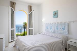 una camera bianca con letto e vista sull'oceano di MuMA Hostel a SantʼAntìoco