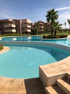 - une piscine dans un complexe avec des palmiers et des bâtiments dans l'établissement Appt vue golf et atlas, à Marrakech