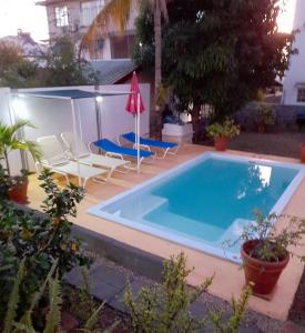 una piscina con 2 sillas y una sombrilla en One bedroom apartement at Flic en Flac 800 m away from the beach with shared pool enclosed garden and wifi, en Flic en Flac