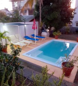 una piscina con 2 sillas y una sombrilla en Charming Apartment in Flic en Flac – 50m² with Pool, en Flic en Flac