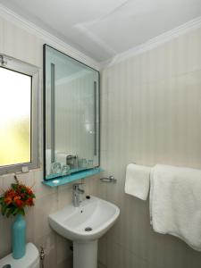 La salle de bains blanche est pourvue d'un lavabo et d'un miroir. dans l'établissement Sunset Beach Hotel, à Sere Kunda NDing