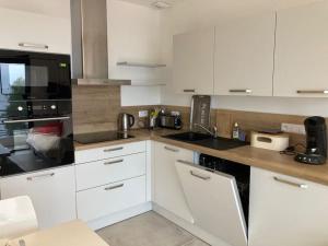 une cuisine avec des armoires blanches et des appareils noirs dans l'établissement Cap Sud,apt 4p,vue mer,pr plage, au Lavandou 12 autres photos