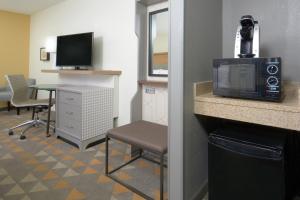 a hotel room with a microwave and a table and chair at Holiday Inn Raleigh Durham Airport, an IHG Hotel in Morrisville
