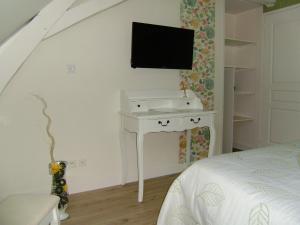 a bedroom with a white desk with a tv on the wall at Chambres d'hôtes Mauvierges in Segré