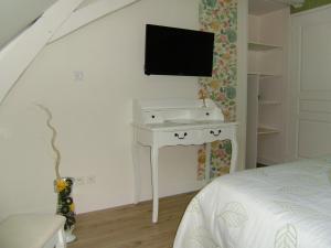 a bedroom with a white desk with a tv on the wall at Chambres d'hôtes Mauvierges in Segré