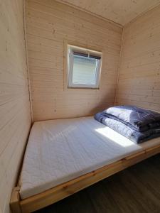 a bed in a small room with a window at NOWE Domki letniskowe Pod Sosenką- 4min od morza! Wicie in Wicie