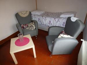two chairs and a table in a room with a bed at Gîte familial avec jardin, terrasse, vélos, Wifi, et animaux acceptés near Saint Pol sur Ternoise - FR-1-376-47 in Fiefs