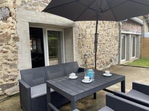 a black table and chairs with an umbrella at Gîte charme & confort avec piscine, terrasse, jardin clos, près de Néris les Bains, animaux acceptés - FR-1-489-344 in Terjat
