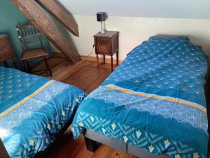 a bedroom with two twin beds and a chair at Gîte charme & confort avec piscine, terrasse, jardin clos, près de Néris les Bains, animaux acceptés - FR-1-489-344 in Terjat
