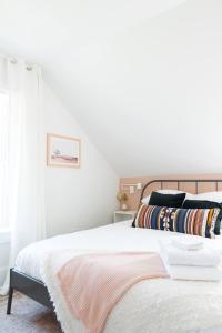 une chambre avec un lit avec des draps blancs et une fenêtre dans l'établissement Downtown Picton 2-Bedroom Boho Suite!, à Picton