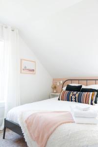 a bedroom with a bed with white sheets and a window at Downtown Picton 2-Bedroom Boho Suite! in Picton