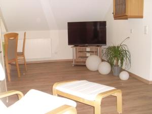 uma sala de estar com uma televisão de ecrã plano e cadeiras em Ferienwohnung am Waldrand em Schmallenberg