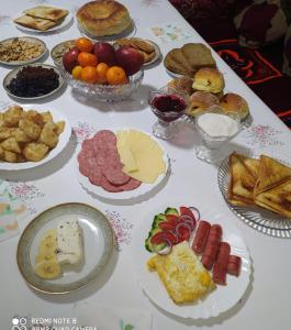 uma mesa com muitos pratos de comida em SunRay Guest House-Hostel em Karakol