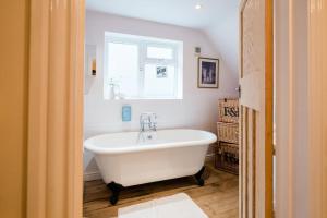 een badkamer met een wit bad en een raam bij Beachcombers in Kent