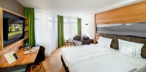 a hotel room with a large bed and a desk at Berghotel Jägerhof ****S in Isny im Allgäu