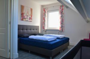 a bedroom with a bed with blue sheets and a window at Woning zeldenrust 4 in Oostkapelle