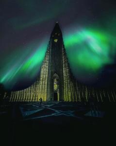 a large building with a clock tower under the northern lights at Stay Iceland apartments - S 46 in Reykjavík
