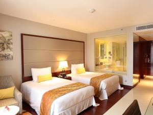 a hotel room with two beds and a chair at Crowne Plaza Kochi, an IHG Hotel in Cochin