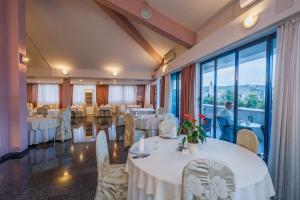 un restaurante con mesas y sillas blancas y ventanas grandes en Hotel Bellevue Trogir en Trogir