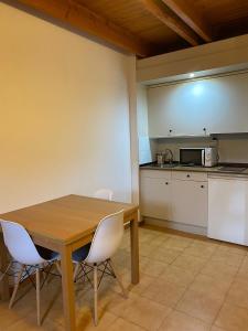 cocina con mesa de madera y sillas blancas en Duplex Sky, muy cerca estación ski, Bonito y acogedor, en Pla de l'Ermita