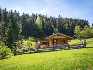 ein Blockhaus auf einem Feld mit einem Zaun in der Unterkunft Alpenchalet Sachrang in Sachrang